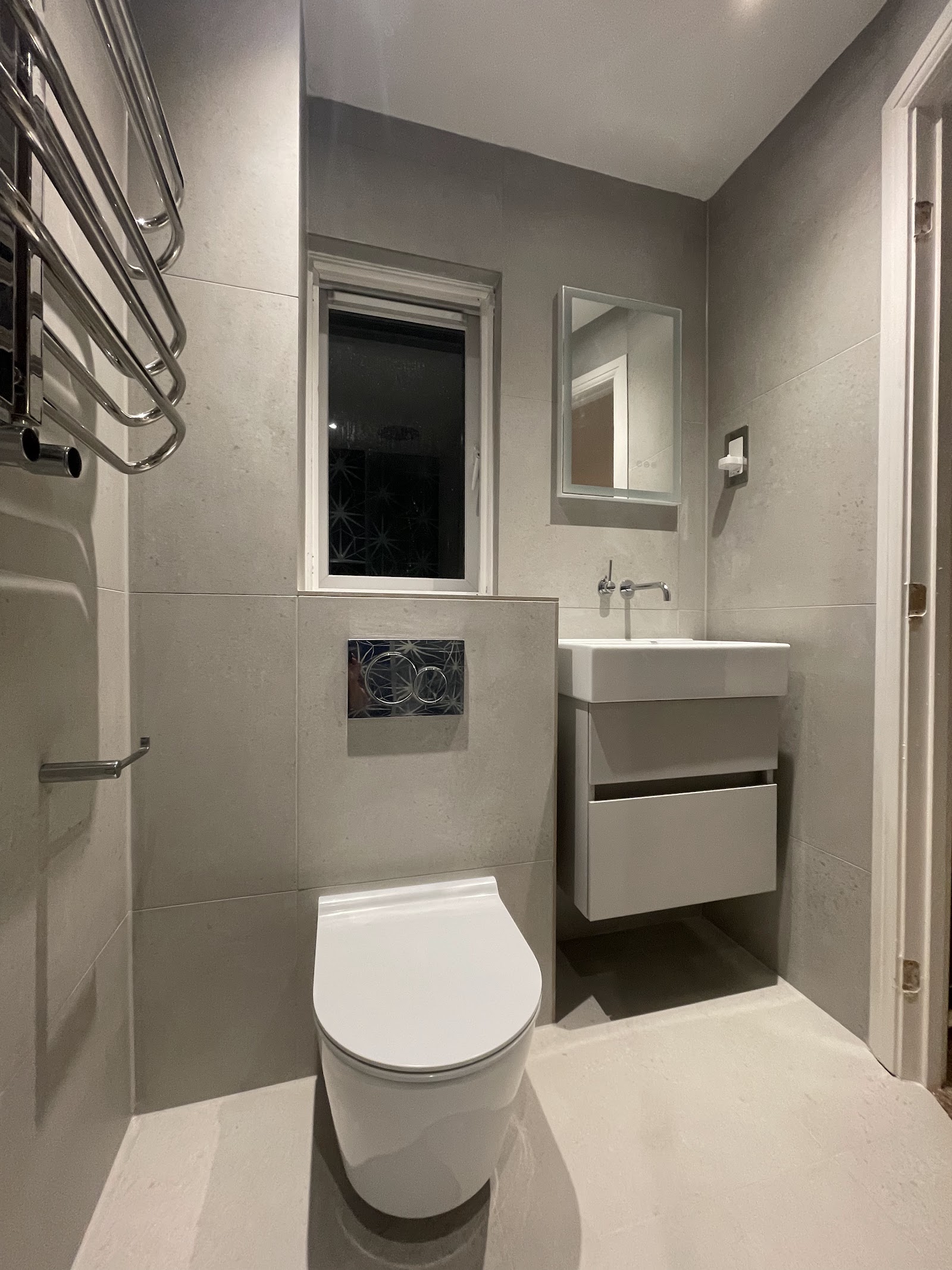 A cloakroom refurbished by South Hampshire Builders, grey porcelain tiling, wall-hung basin and WC