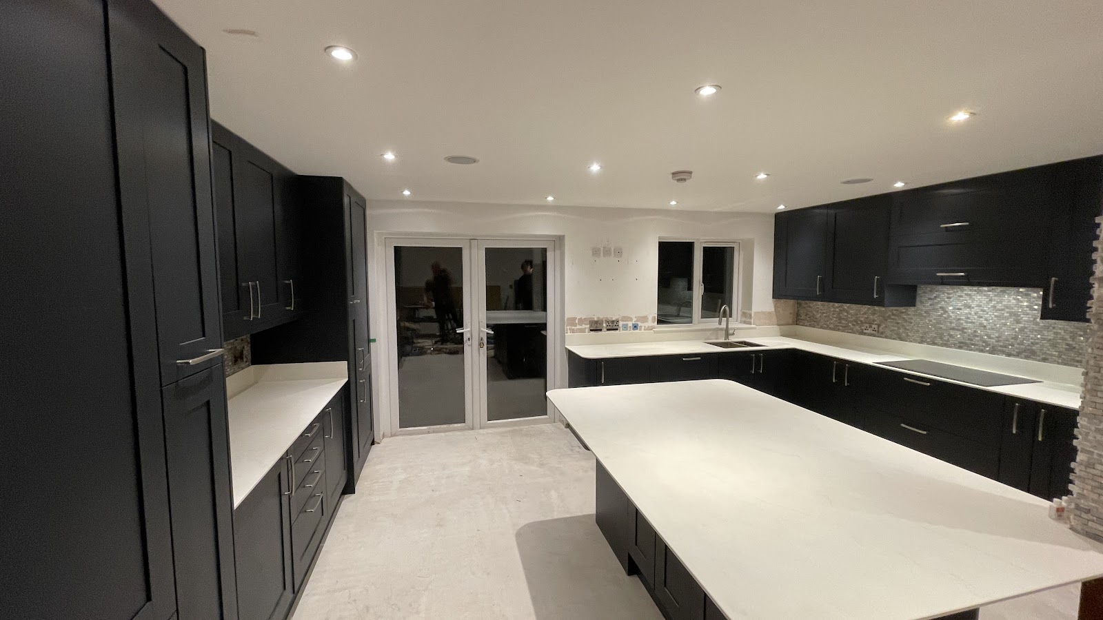 A finished dark-cabinet kitchen with white worktops, fitted by South Hampshire Builders